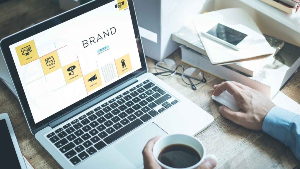 en un computador están diferentes elementos escenciales del branding y una persona está viendo con un café en la mano en una oficina Cómo elegir una consultora de branding estratégico en Colombia feeling brand