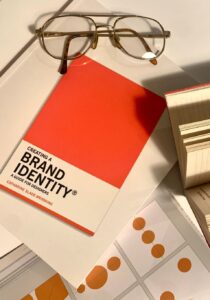 libro denominado Brand Identity con algunas muestras de color debajo y otros libros alrededor y unas gafas en la parte superior consultora de branding estratégico feeling brand
